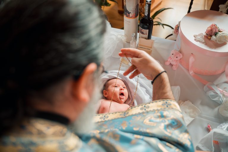 Preotul îi așază micuței Aria lănțișorul sfințit, în timpul botezului din Paris