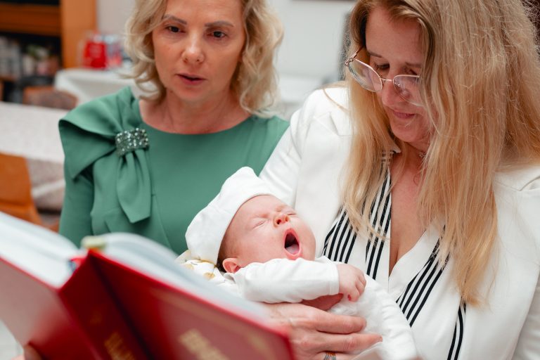 Olivia dormind în brațele nașei, lumină naturală în biserică