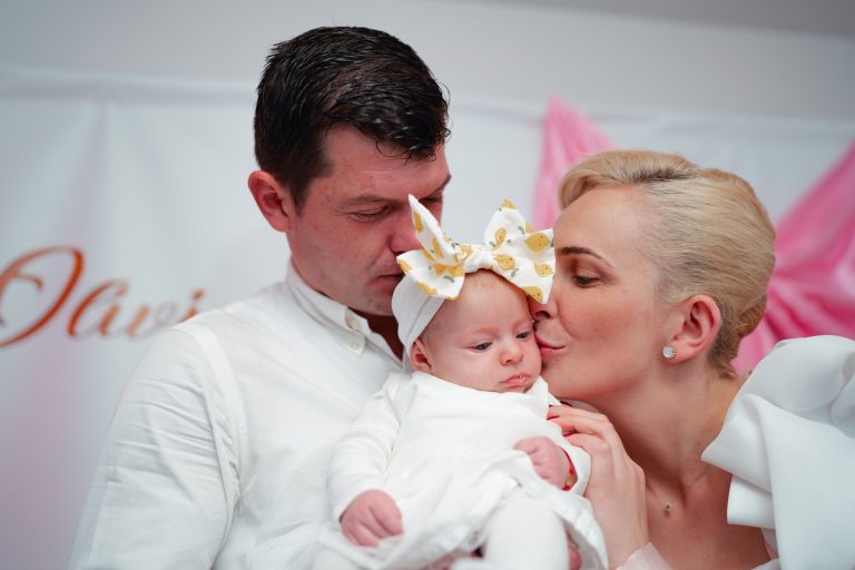 Tatăl o ține pe Olivia în brațe, mama o sărută pe obraz