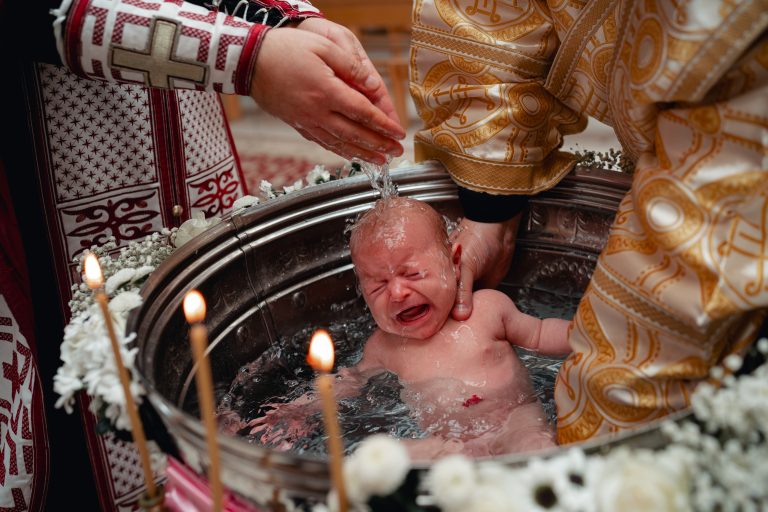 Olivia în cristelniță, prim-plan cu mâna preotului și apa sfințită