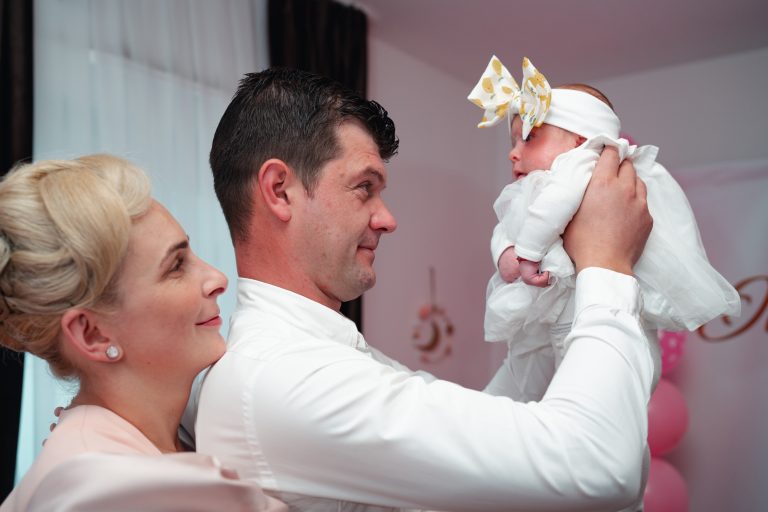 Tatăl o ține pe Olivia la nivelul ochilor, mama zâmbește lângă ei