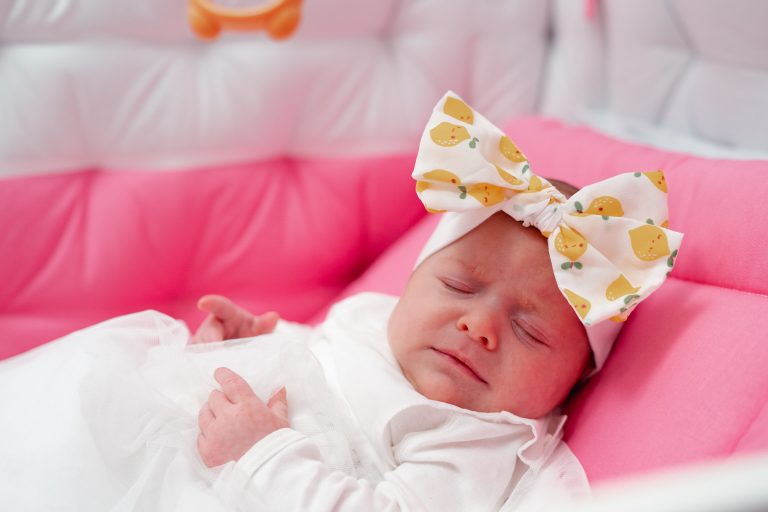 Olivia dormind în pătuțul roz, fotografie caldă și blândă